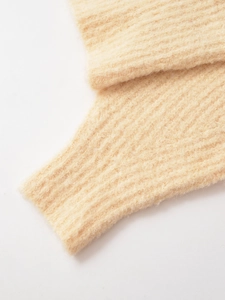 Gros plan détaillé sur les poignets en tricot côtelé crème et la texture mohair