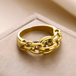Macro detail of a thick gold-plated Cuban chain ring on a luxury champagne jewelry box