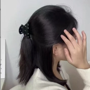 Detailed side view of a black bow hair claw clip with star-like pearl accents for women