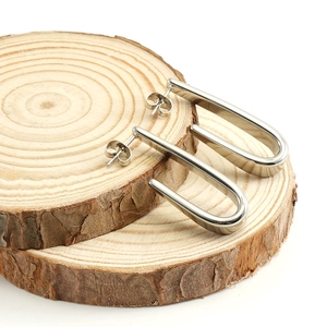Boucles d'oreilles en acier inoxydable argenté en forme de U sur support en bois naturel