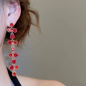 Close-up of elegant red resin rose tassel earrings with crystals worn by a model