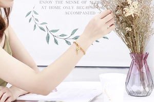 Lifestyle shot of a delicate gold heart and key charm bracelet worn on a female wrist