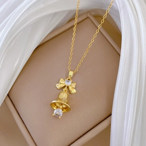 Close-up of golden bow and bell pendant necklace with sparkling heart-shaped crystals