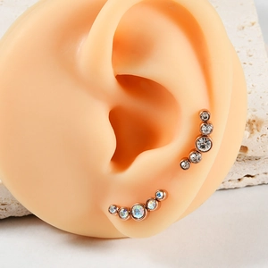 Macro view of rose gold ear climbers with five white zircons on a silicone ear model