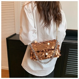 Detail of rose gold sequin handbag with thick silver metal chain on model