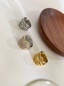Detailed top view of triple-layered criss-cross rings in gold, silver, and tricolor finishes
