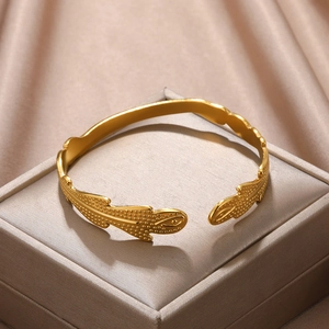 Detail of gold-plated open bangle featuring textured scale pattern on satin display