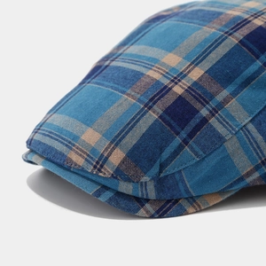 Close-up of blue and tan plaid pattern on a cotton blend newsboy cap with neat stitching
