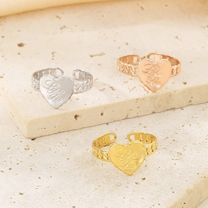 Detailed view of heart-shaped open rings in gold, silver, and rose gold on stone