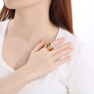 Close-up of a wide gold-tone sculpted ring worn on a finger with a metallic finish