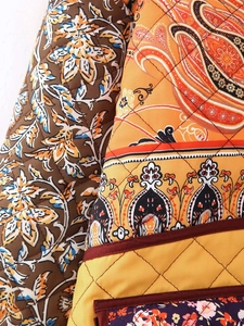 Detailed close-up of ethnic paisley floral patterns and quilted texture on a cotton jacket