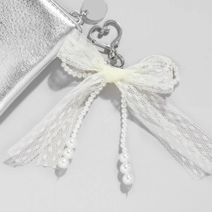Beige lace bow and white faux pearl keychain with heart charm on a silver purse