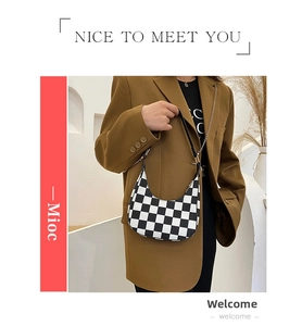 Detail of checkered crescent bag featuring vintage black and white patterns and metal chain