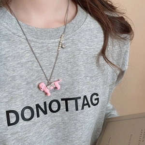 Detail of a pink dachshund pendant necklace with pearls and zircon bow on a silver chain