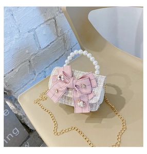 Detailed view of tweed mini crossbody bag with pink bow, pearl handle and gold chain