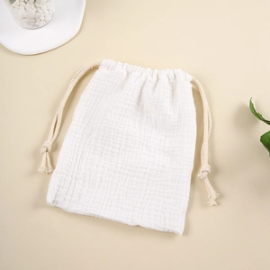 Detail of white cotton muslin drawstring storage bag with soft texture and natural rope ties