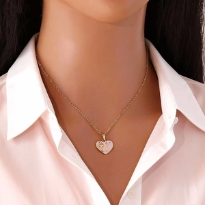Golden heart pendant necklace featuring star and moon details on pink enamel surface