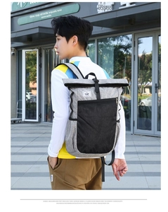 Waterproof business travel backpack with roll-top closure shown on a male model outdoors