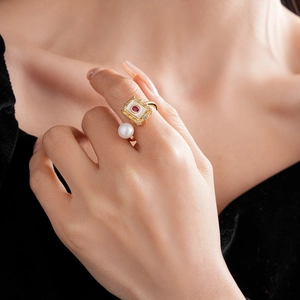 Close-up of gold-plated square ring with pearl and red stone on hand model
