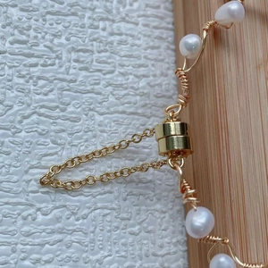 Macro shot of handcrafted gold wire wrap pearls and cylindrical magnetic clasp detail