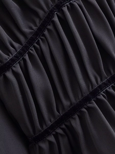 Detailed close-up of pleated black chiffon fabric with velvet ribbon trim and texture