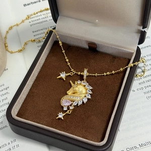 Macro shot of 18k gold plated unicorn necklace with pink zircon in luxury box