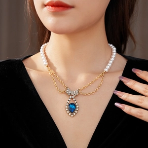 Detail of vintage necklace with pearls, gold chains, rhinestone bow and blue teardrop gem