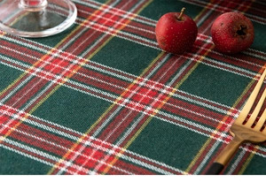 Close-up of red and green plaid Christmas table runner with linen texture and festive decor