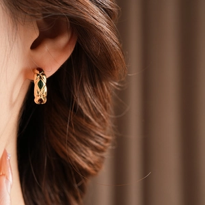 Close-up of a vintage-style gold C-shaped earring with elegant quilted pattern texture