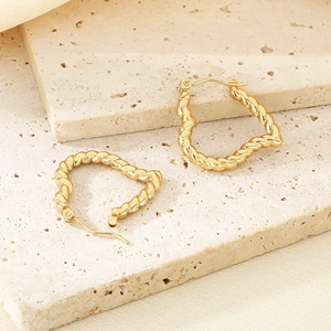 Elegant gold twisted rope heart hoop earrings displayed on a minimalist stone texture