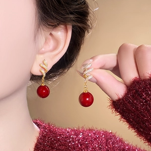 Macro detail of red pearl earrings with golden spiral and inlaid crystal accents