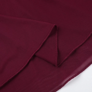 Détail du tissu en maille bordeaux montrant la texture respirante et l'ourlet de la robe