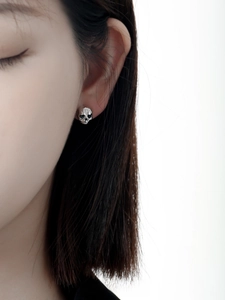 Close-up of a 925 silver skull stud earring with punk style worn on a model's ear