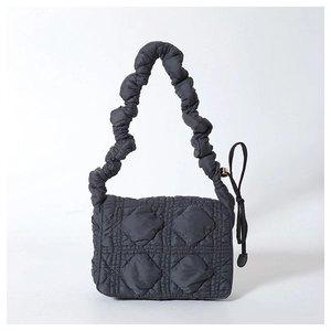 Detail of black quilted nylon fabric with unique pleated shoulder strap and drawstring