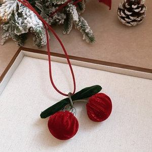 Detailed view of red velvet cherry charm with green leaves on a festive wooden tray