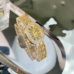 Detailed macro of gold crystal-encrusted watch on reflective silver tray surface