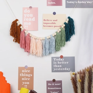 Bohemian colorful cotton tassel garland with wooden beads hanging on a white wall