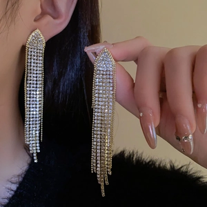 Macro shot of gold tassel earrings with shimmering crystals on an elegant ear cuff