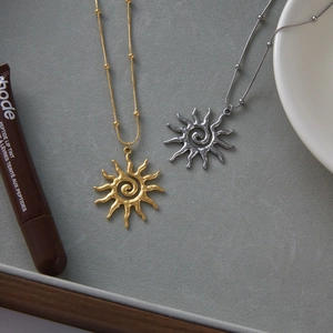 Detailed view of 18k gold and silver sun pendant necklaces with spiral hammered texture