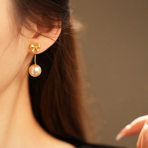 Close-up of gold bowknot earrings with pearls on model in a soft vintage style