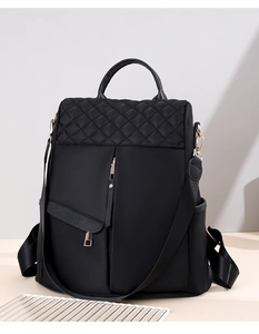 Detail of black quilted nylon backpack featuring elegant gold zippers and hardware accents