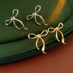 Gros plan détaillé de boucles d'oreilles nœuds dorées et argentées sur velours vert