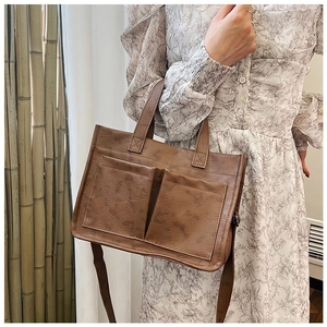 Detail of retro brown PU leather tote bag with front square pockets and adjustable straps