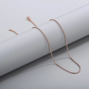 Detail showing high-polish rose gold snake chain texture on a minimalist jewelry stand