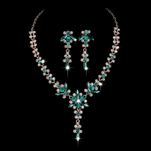 Elegant gold bridal jewelry set with sparkling green and white crystals on black background