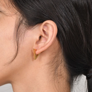Macro shot of minimalist gold triangular hoop earring worn on earlobe for modern style