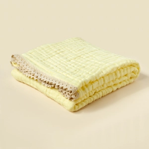 Detail of soft 6-layer cotton muslin baby blanket with delicate lace trim edging