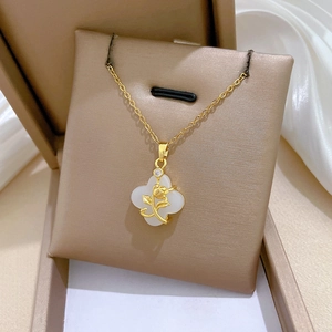 Macro shot of gold four-leaf clover pendant with rose detail and crystal in a gift box