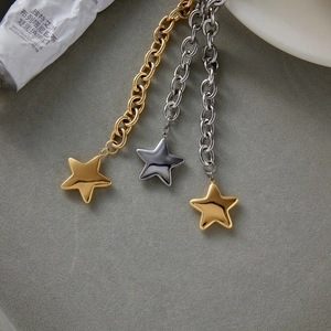 Close-up of gold and silver stainless steel star charm bracelets on a grey textured surface