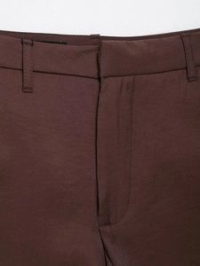 Macro detail of the waist and belt loops on brown tailored shorts with fine stitching